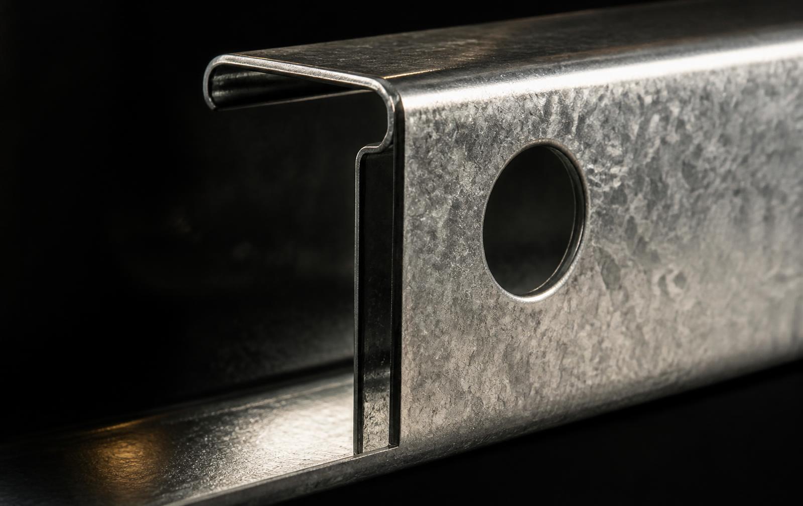Detalle macro de un perfil de acero galvanizado con perforación CNC